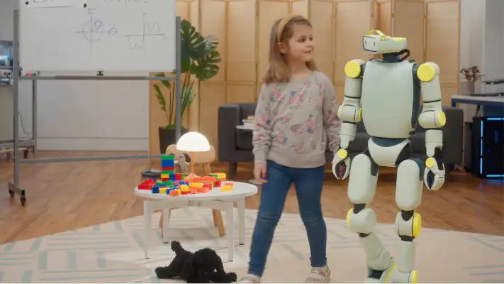 Child standing with humanoid robot in classroom with building blocks and dog on floor.